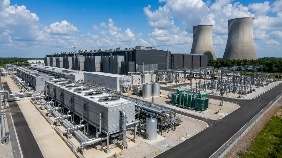 A large technology campus stands near cooling towers and substation equipment, emphasizing the relationship between data centers, power generation, grid capacity, and the energy needs of modern...