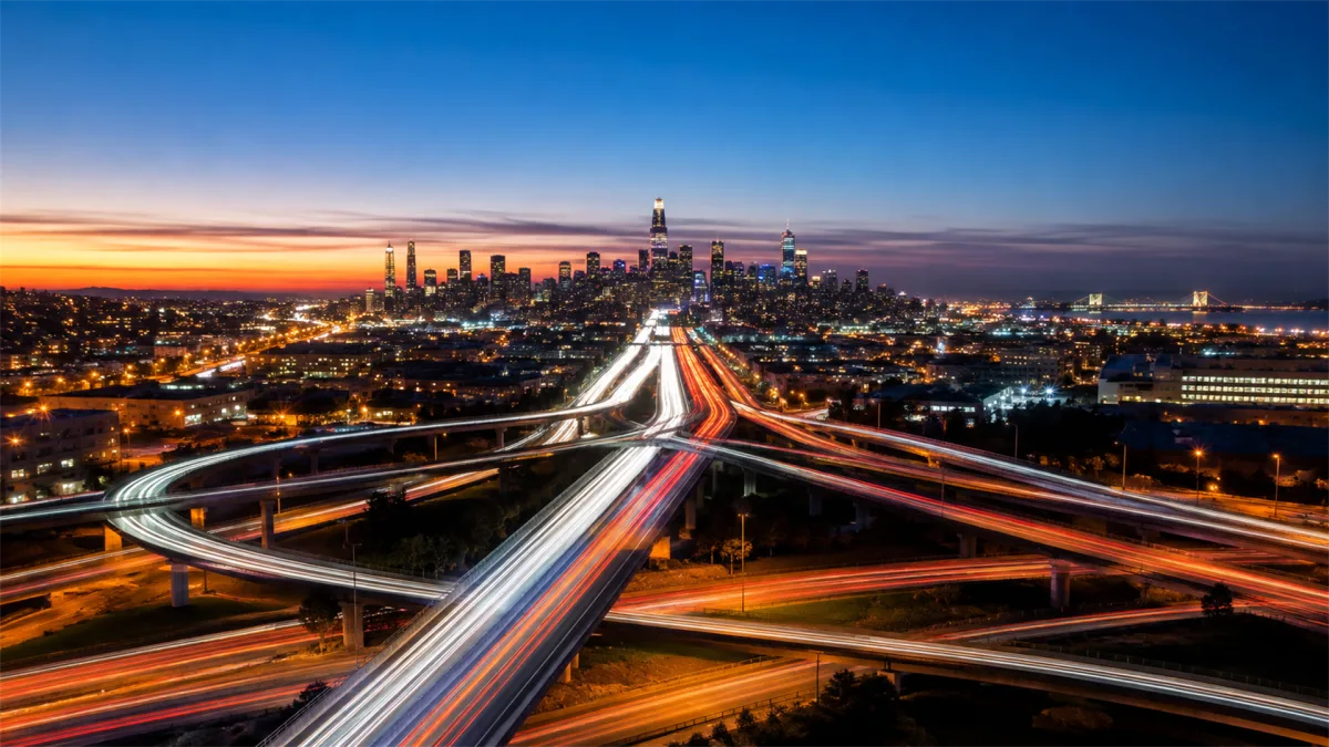 Long exposure traffic trails sweep through elevated roadways into a city skyline at dusk, creating a connected transport metaphor for smart roads, urban data flows, navigation systems, and...