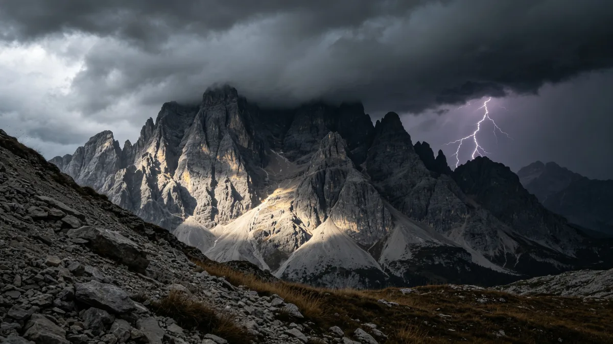 lightning and storm clouds strike behind jagged gray mountain ridges.