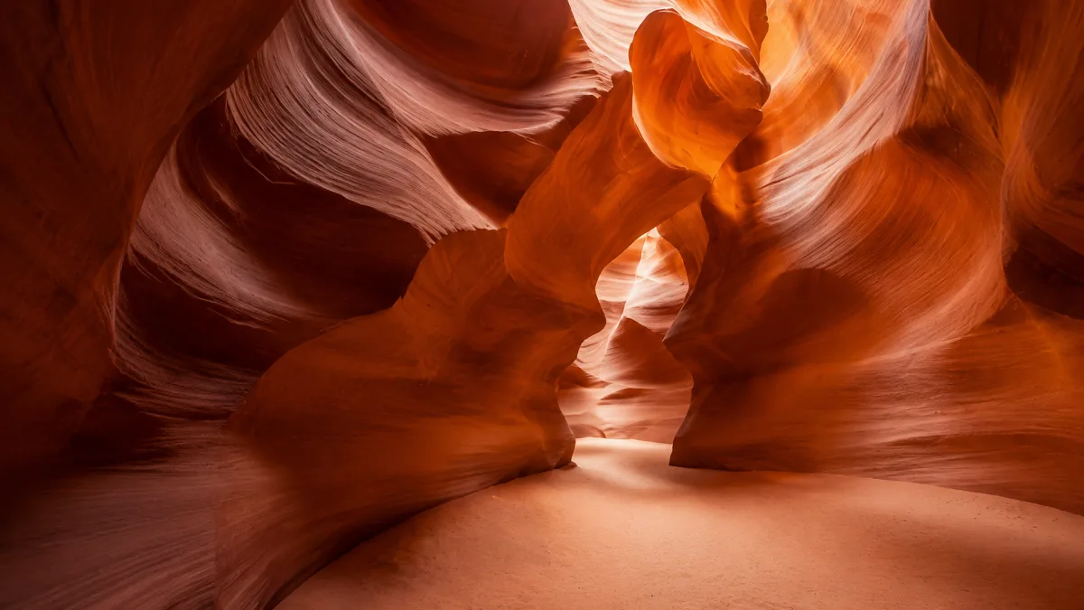 Warm light pours through a narrow red sandstone slot canyon.