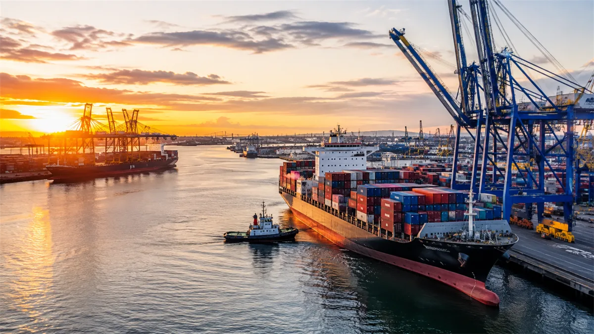 container ship loading under cranes at sunset harbor