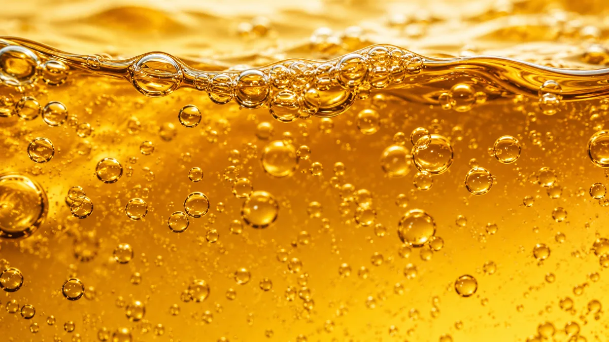 Golden bubbles fill a liquid surface, suggesting biofuel, fuel chemistry, and energy material.