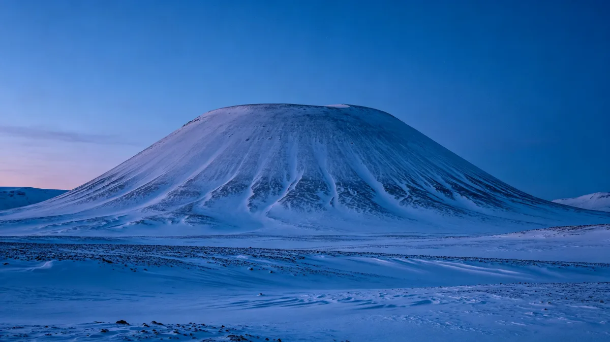 soft white snow dunes stretch under a pastel blue and pink horizon.